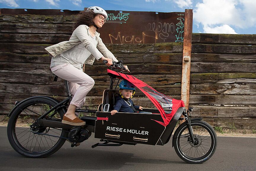 Mutter und Kind mit dem E-Bike Lastenrad unterwegs Mutter und Kind mit dem E-Bike Lastenrad unterwegs