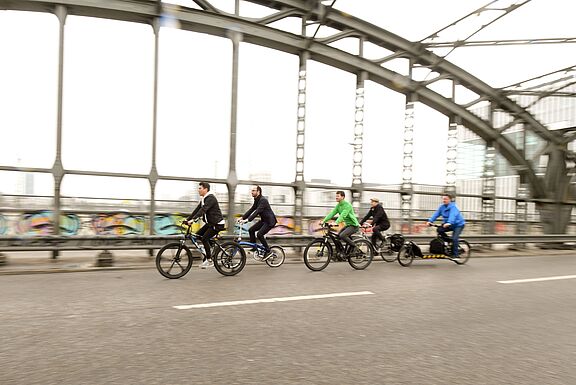 Mehrere Radfahrer fahren über eine Brücke.